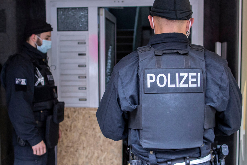 Polizisten stehen bei einer Razzia vor einem Hauseingang. (Symbolbild)