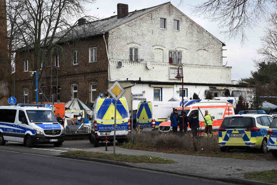 Einsatzkräfte der Polizei und Rettungsdienst stehen vor einem Haus.