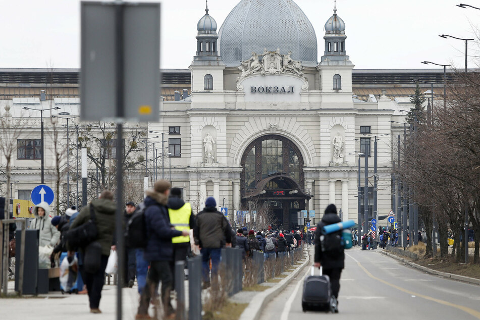 Hundreds of people wait outside a train station to get a train out of the country towards Poland in Lviv, Ukraine.