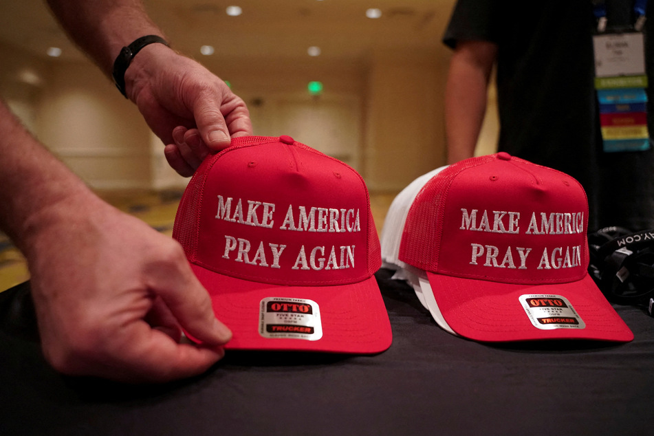 People arrange "Make America Pray Again" caps for display at the 2024 National Religious Broadcasters Association International Christian Media Convention.