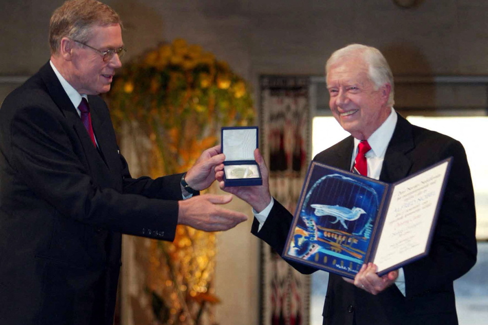 Former US president Jimmy Carter (r.) receives the 2002 Nobel Peace Prize from the chairman of the Norwegian Nobel Committee Gunnar Berge (l.) during a ceremony in the Oslo City Hall 10 December 2002.