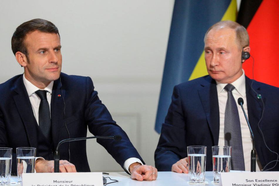 Emmanuel Macron (l), Präsident von Frankreich, und Wladimir Putin, Präsident von Russland, sitzen auf zu gemeinsamen Pressekonferenz im Pariser Schloss Elysee.
