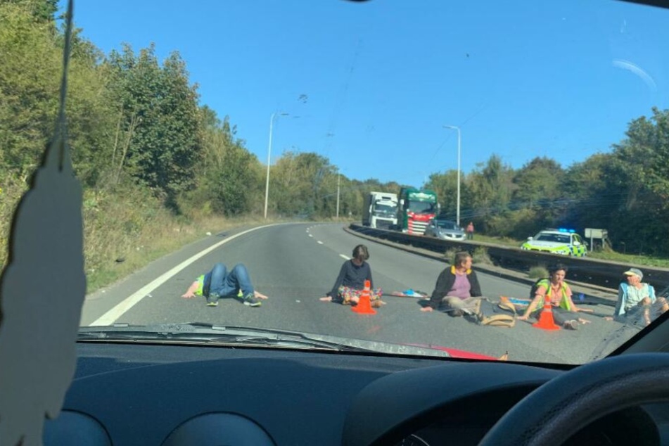Fünf Demonstranten kleben freiwillig an der Autobahn fest.