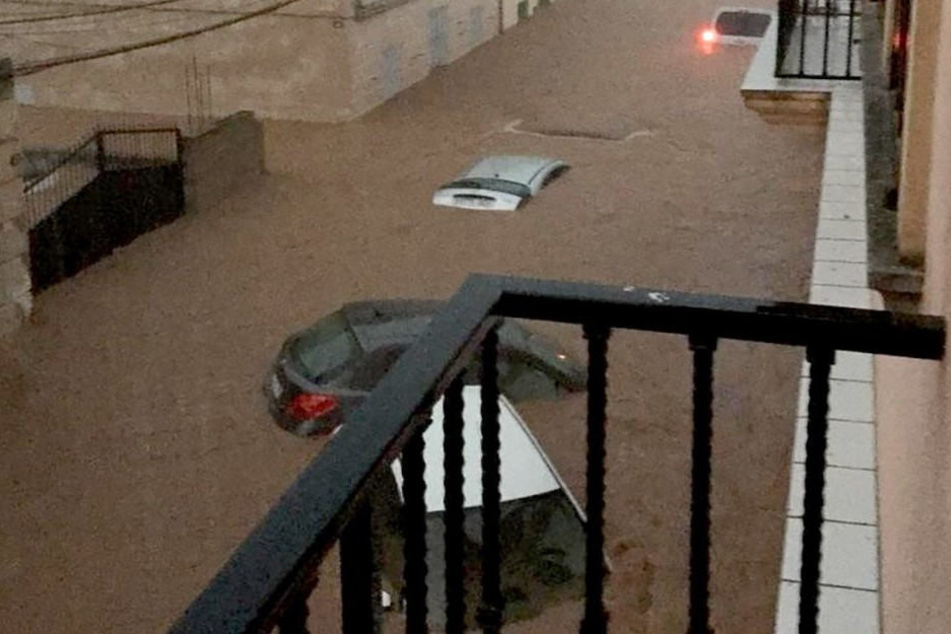 Die heftigen Wassermassen treiben die Autos vor sich her.