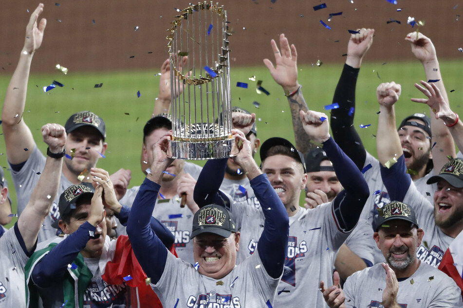 Atlanta Braves manager Brian Snitker (c) holds high the Commissioner's Trophy after winning the 2021 World Series.