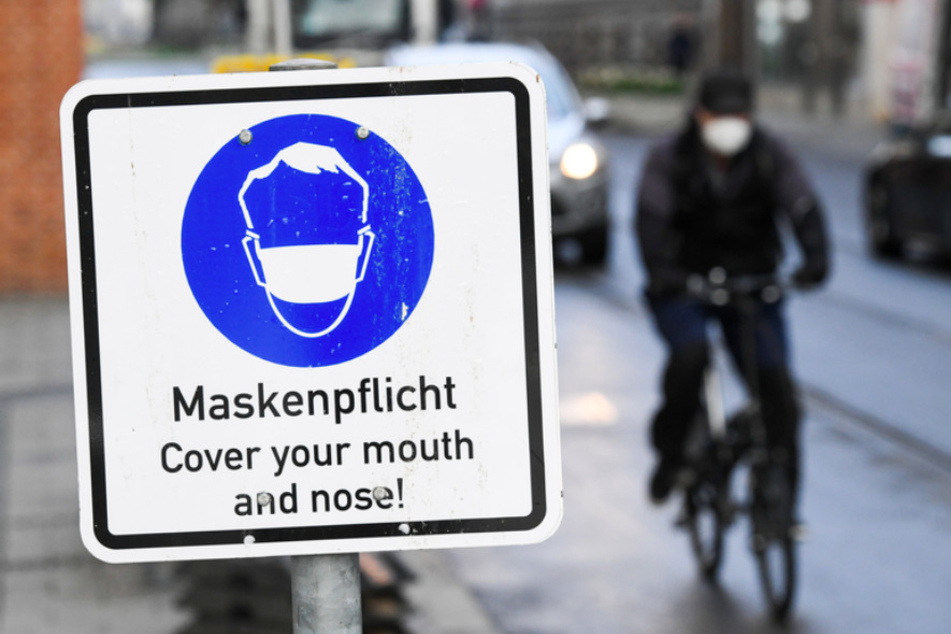 Ein Radfahrer fährt an einem Hinweisschild zur Maskenpflicht in der Münchner Innenstadt vorbei.