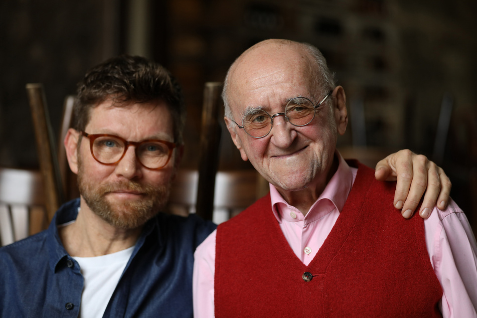 Scott Biolek-Ritchie (l), Adoptivsohn von Alfred Biolek, und Alfred Biolek stehen zusammen in einem Restaurant.