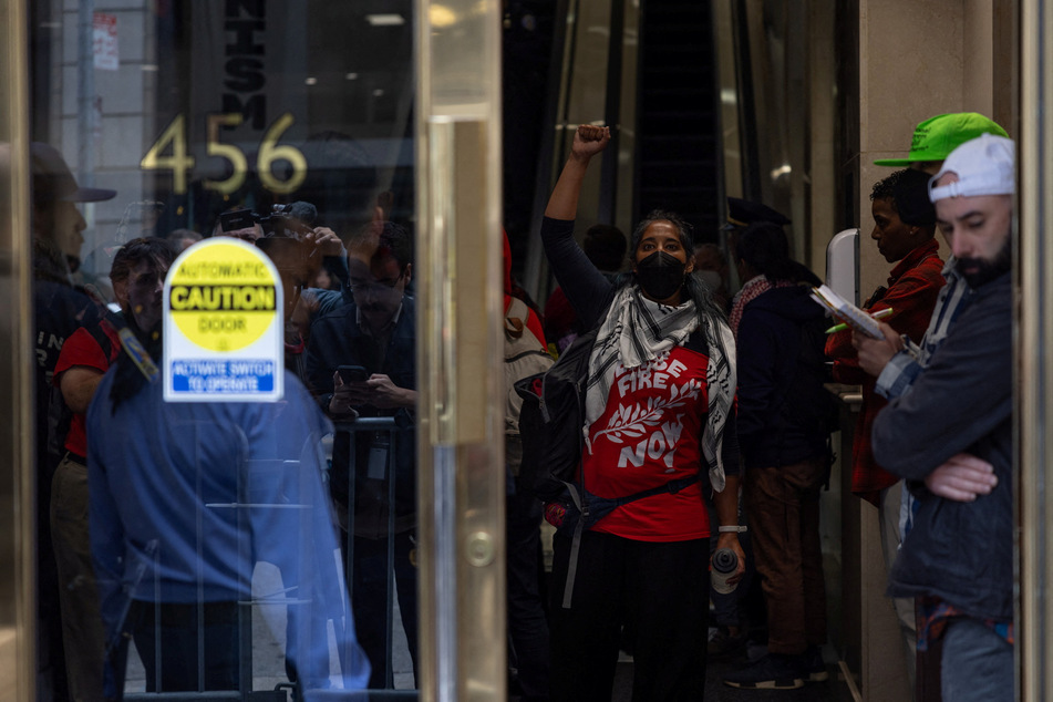 A woman raises her fist in the air as pro-Palestinian protesters occupy the building lobby of the Israeli Consulate in downtown San Francisco, California.