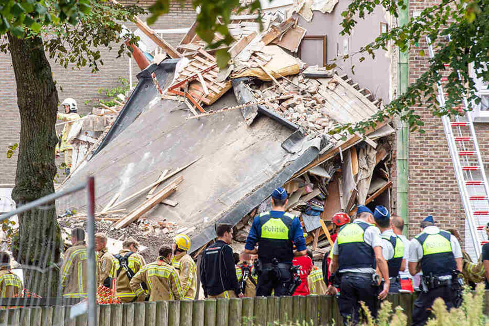 Rettungskräfte von Polizei und Feuerwehr stehen vor den Trümmern eines zerstörten Gebäudes. Bei einer Explosion im belgischen Antwerpen sind mehrere Menschen verletzt worden.