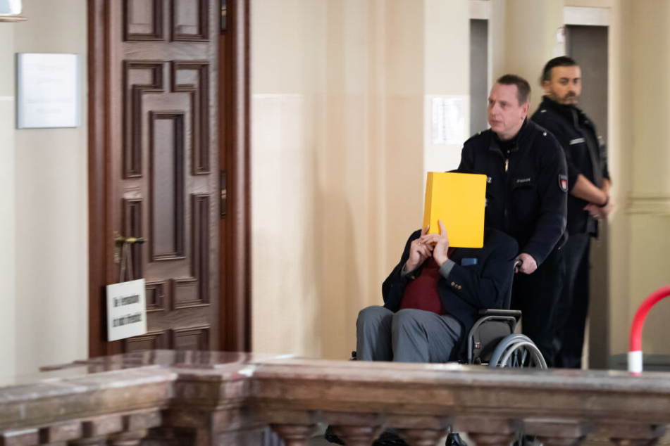 Der 93-jährige Angeklagte wird von einem Justizbeamten in den Sitzungssaal geschoben.
