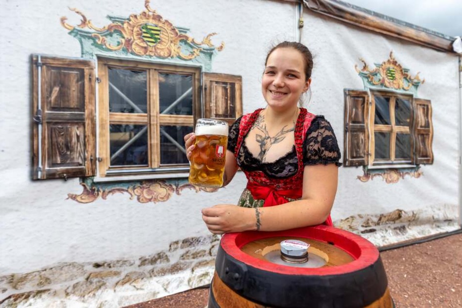 Service-Kraft Carolin (26) mit einer Maß Bier und einem Bierfass vor dem Festzelt.
