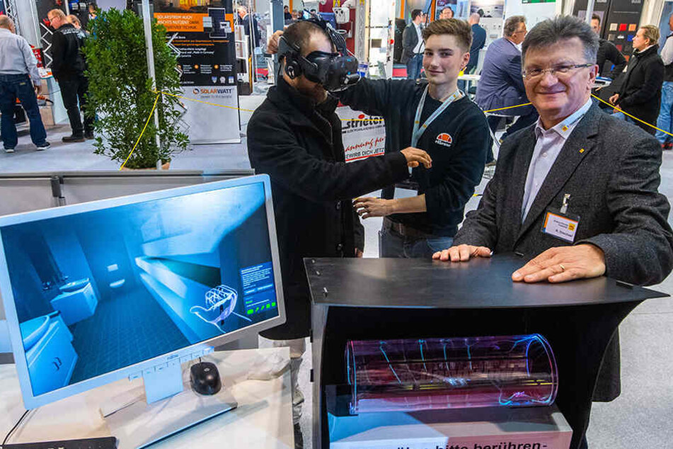 Carsten Tschirner schaut sich mit VR-Brille im virtuellen Haus um, Marvin Geisler (M.) und Robby Drechsel von der Elektroinnung erklären das System.