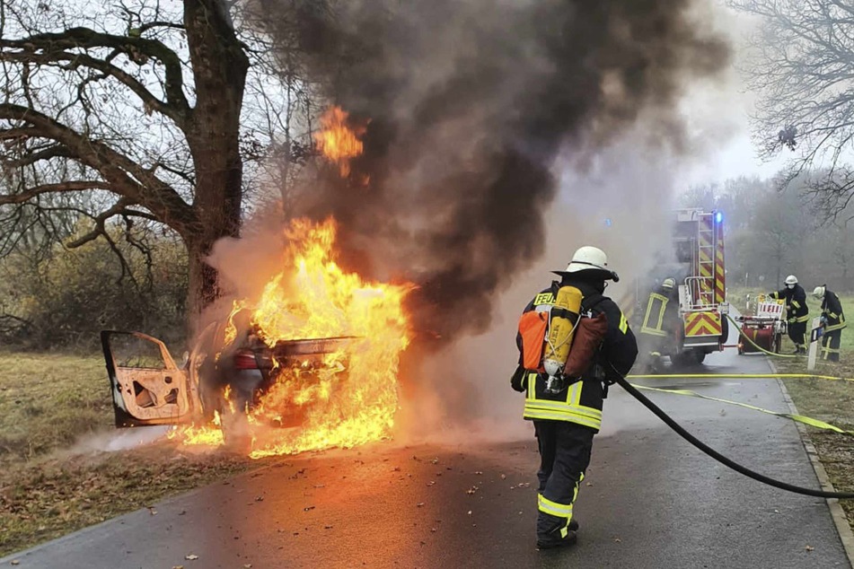 Feuerwehrleute versuchen ein brennendes Auto zu löschen.