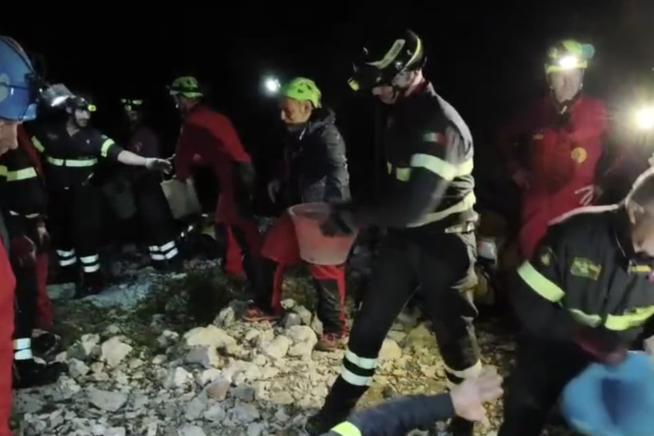 Rund 30 Einsatzkräfte versuchen per Hand, den versperrten Höhleneingang freizulegen.