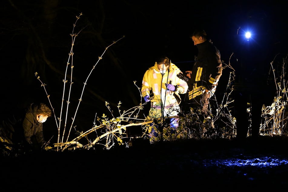 Polizisten mit Schutzmasken untersuchen die Leiche einer Frau, die in einem Düsseldorfer Waldstück entdeckt wurde.