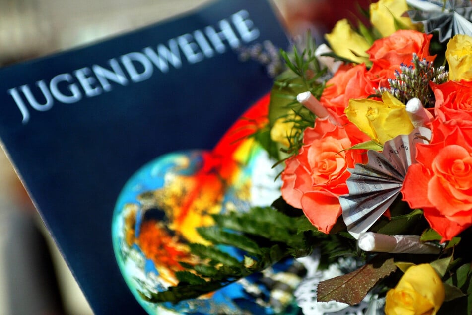 Eine Jugendweihe-Urkunde liegt neben einen Blumenstrauß.