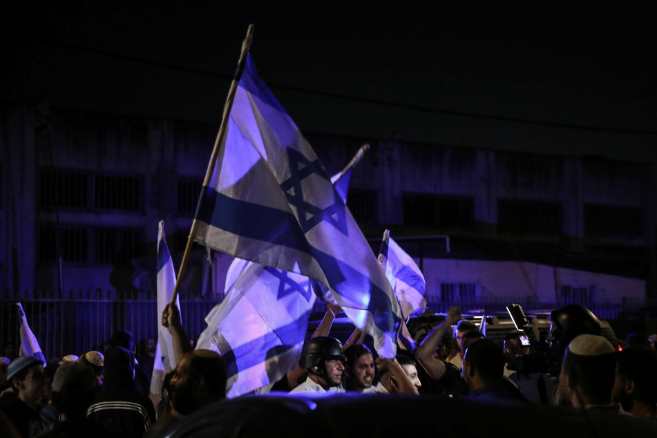 Jüdische Demonstranten schwenken israelische Flaggen während der nächtlichen Ausgangssperre in Lod.
