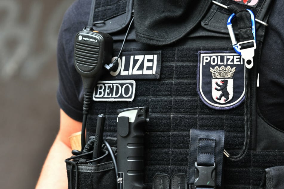 Ein Polizeibeamter steht in Berlin-Neukölln bei einer Razzia vor einem Haus. (Archivbild, Symbolbild)