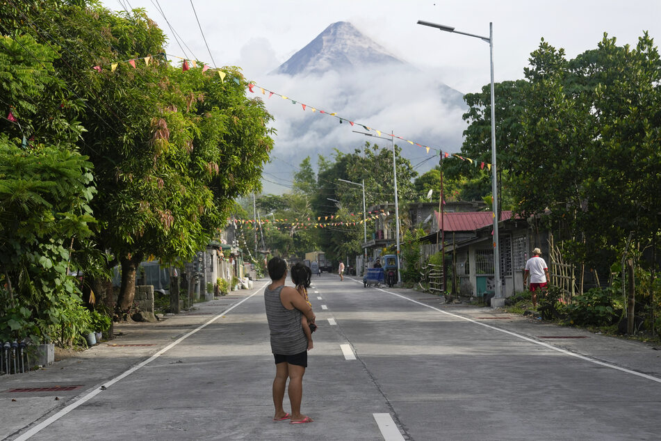 Eine Frau und ein Mädchen blicken auf den Feuerberg nahe Legazpi im Nordosten der Philippinen.