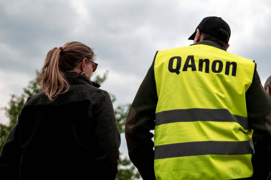 Ein Teilnehmer der Demonstrationen gegen Corona-Maßnahmen trägt eine Warnweste mit der Aufschrift "QAnon".