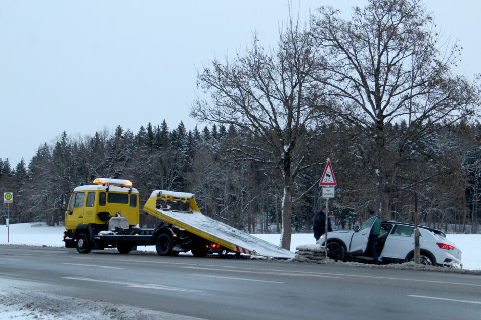 Ein Abschleppwagen steht vor einem beschädigten Auto, das nach Schneefällen im Landkreis Miesbach in den Straßengraben geraten war.