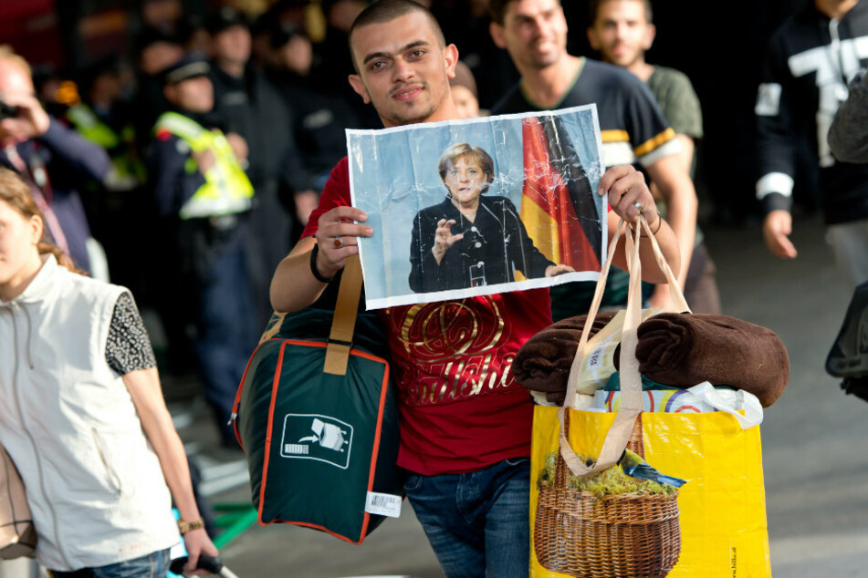 Ein Flüchtling, der kurz zuvor mit einem Zug angekommen ist, läuft 2015 auf dem Hauptbahnhof über den Bahnsteig und hält dabei ein Foto von Angela Merkel in den Händen. (Archivbild)