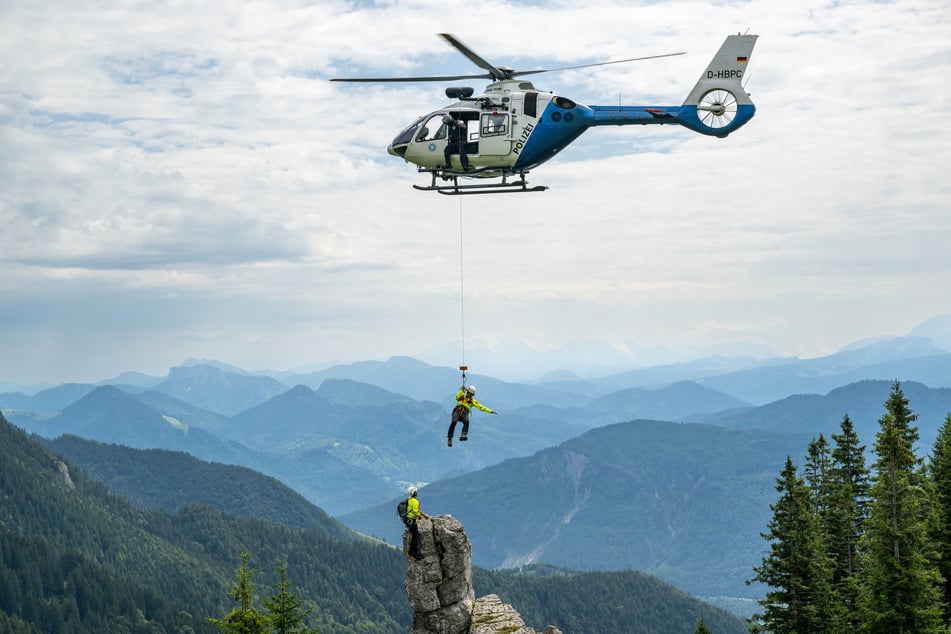 Ein Polizeihubschrauber zeigt während einer Luftrettungs-Übung an der Kampenwand das Abseilen einer Person.