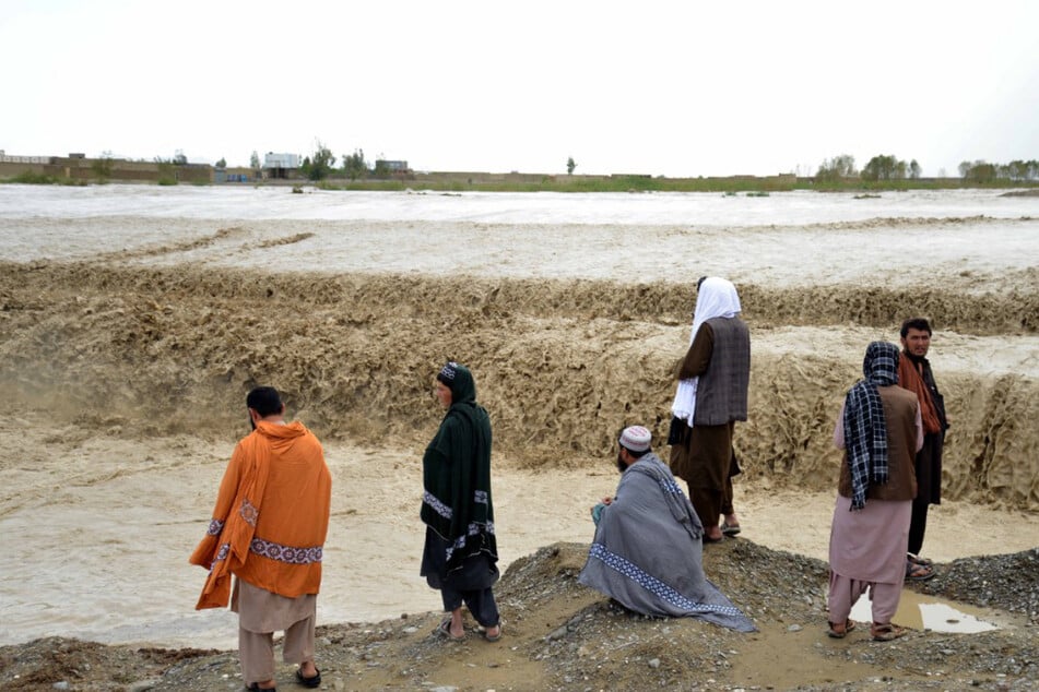 Afghanen warten darauf, ein überschwemmtes Gebiet im Bezirk Spin Boldak in der Provinz Kandahar durchqueren zu können.
