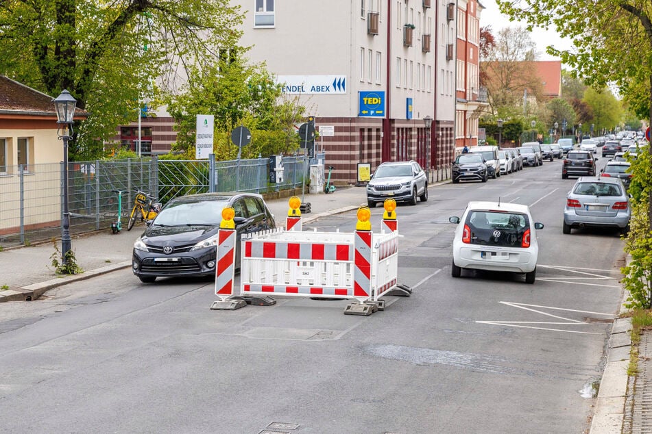 Wegen eines großen Lochs muss mitten auf der Industriestraße eine Absperrung stehen. Autos können beidseitig vorbeifahren.