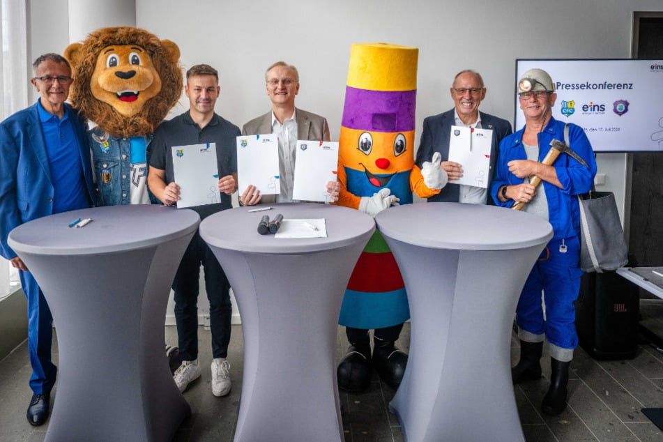Im Bild (v.l.): Frank Löbe (stellv. Vorstandsvorsitzender CFC), CFC-Maskottchen Malik, Tommy Haeder (Leiter Geschäftsstelle CFC), eins-Geschäftsführer Roland Warner, das eins-Maskottchen "Schorsch", Roland Frötschner (Präsident FC Erzgebirge Aue) sowie "Bergmann" Reinhard Lange