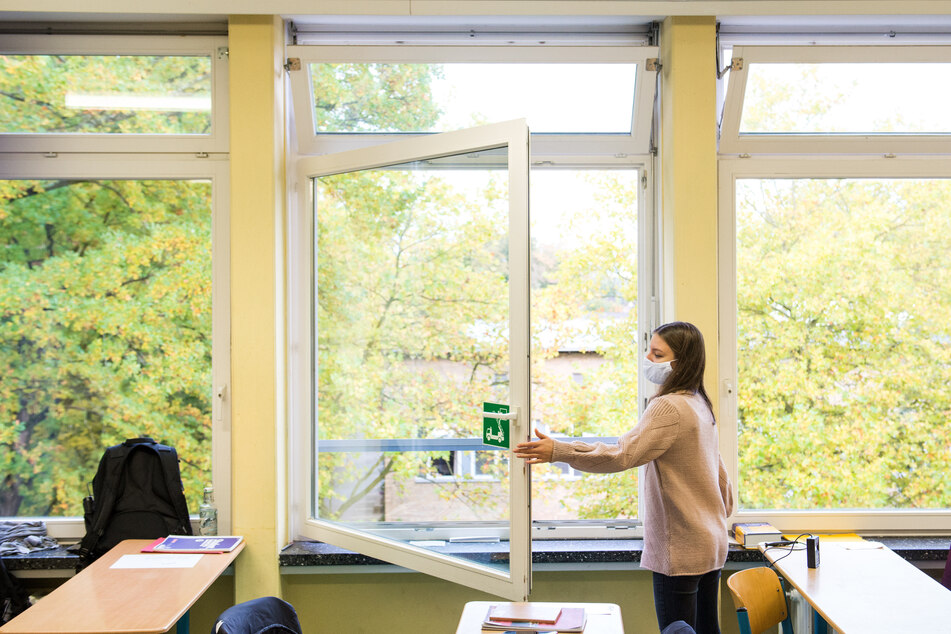 Eine Schülerin der Oberstufe öffnet das Fenster in einem Klassenraum.