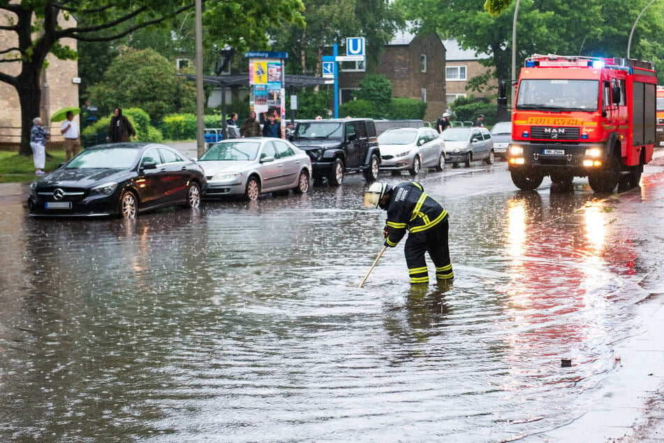 Eine Feuerwehrfrau steht am Donnerstag im Hamburger Stadtteil Öjendorf auf einer von starkem Regen überfluteten Straße. Am Freitag geht es mit dem Unwetter weiter.