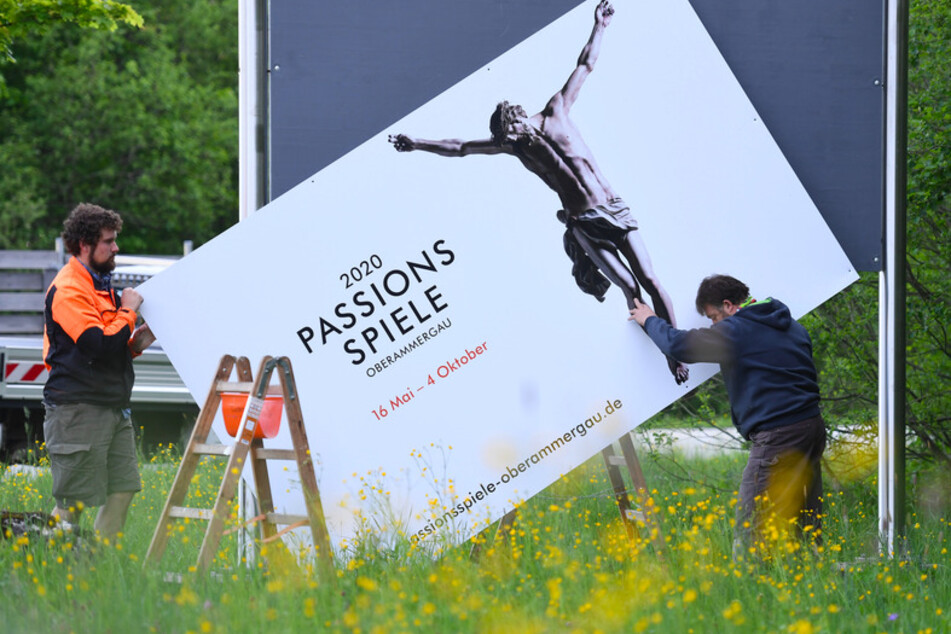 Arbeiter bauen eines der Werbeplakate der Passionsspiele 2020 ab. Oberammergau schaut auf das Jahr 2022: Dann will der Ort seine weltberühmten Passionsspiele nachholen.