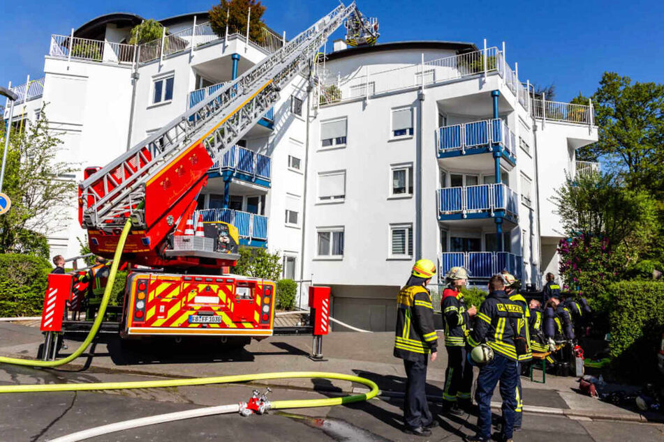 Einsatzkräfte der Feuerwehr stehen vor dem Wohnhaus in Bad Nauheim, in dem zwei männliche Leichen entdeckt wurden.