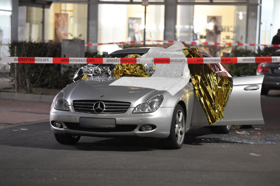 Ein Auto ist mit Thermofolie abgedeckt, neben dem Wagen liegen Glassplitter, der Tatort ist mit Polizei-Band abgesperrt (Archivfoto).
