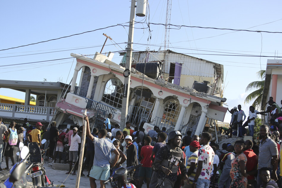 Menschen versammeln sich vor dem Hotel Petit Pas, das durch das Erdbeben in Les Cayes, Haiti, am Samstag, 14. August 2021, zerstört wurde.