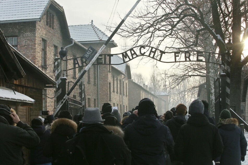 Menschen stehen vor dem Haupttor des früheren Konzentrationslagers Auschwitz mit dem Schriftzug "Arbeit macht frei". Sowjetische Truppen hatten das deutsche Vernichtungslager im besetzten Polen am 27. Januar 1945 befreit.