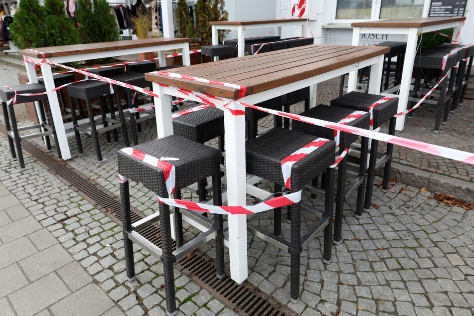 Mit rot-weißem Flatterband abgesperrt sind die Sitzgelegenheiten vor einer gastronomischen Einrichtung. (Symbolbild)