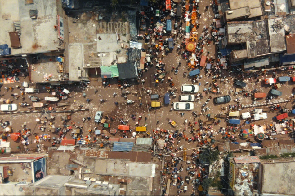 Pures Chaos: Menschen, Rikschas und Autos laufen und fahren in Delhi wild durcheinander.