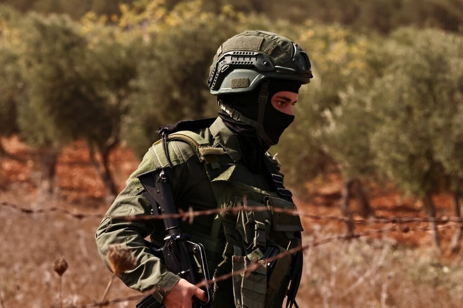 An Israeli soldier orders Palestinian farmers and volunteers to leave the field during the olive harvest season in the village of Qusra, south of Nablus, in the occupied West Bank.