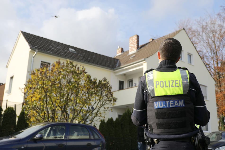 Ein Polizist steuert zur Spurensicherung eine Drohne über einem Grundstück.
