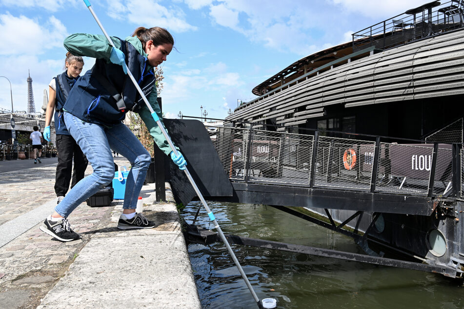 An employee of the company Fluidion collects a sample of water from the Seine to analyze its composition ahead of the 2024 Paris Olympics, near the Pont Alexandre III in Paris, on August 4, 2023.