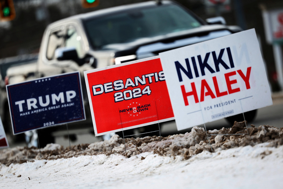 Signs for Donald Trump, Ron DeSantis, and Nikki Haley are set up in a snow bank on a roadside ahead of the New Hampshire presidential primary election in Nashua on January 20, 2024.