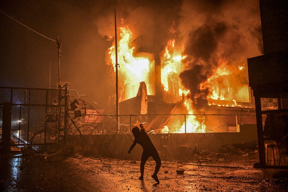 Ein libanesischer Demonstrant wirft Steine auf ein brennendes Gebäude in der Nähe der US-Botschaft während einer Solidaritätsdemonstration mit der Bevölkerung des Gazastreifens.