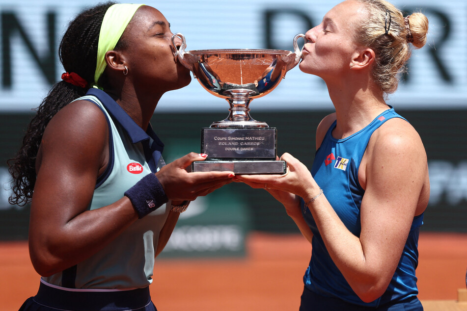 Coco Gauff of the US (l.) and Katerina Siniakova of the Czech Republic kiss their trophy after winning the women's doubles match final at the French Open.