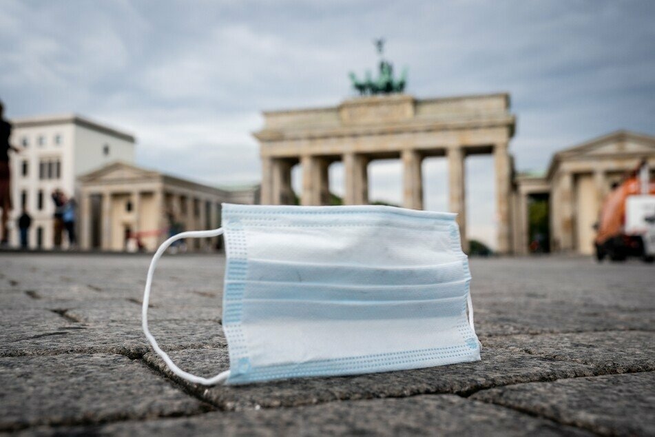 Ein Mund-Nasen-Schutz wird vom Wind über den Pariser Platz vor dem Brandenburger Tor geweht.