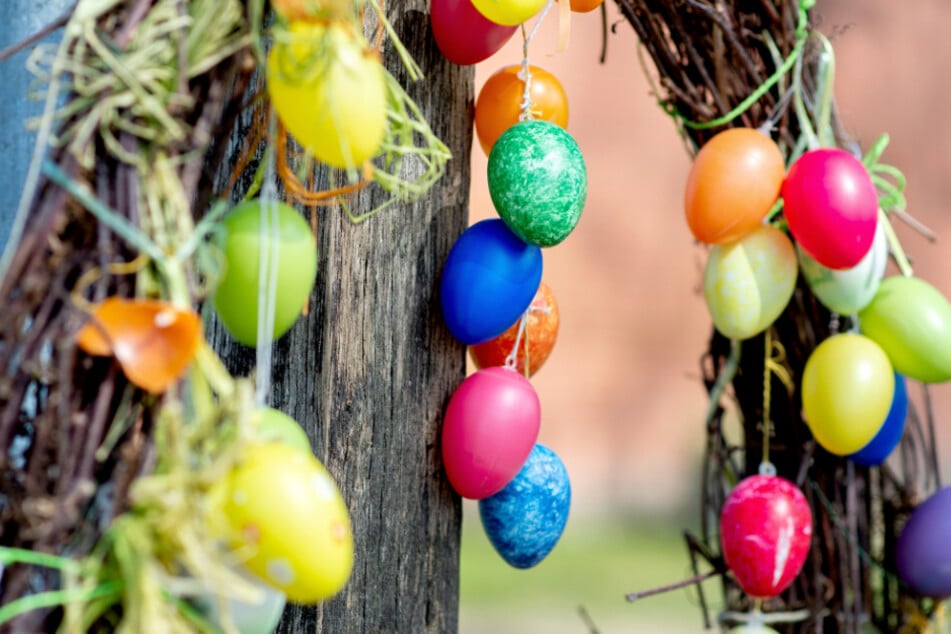Bunte Ostereier hängen als Schmuck an einem Zaun.