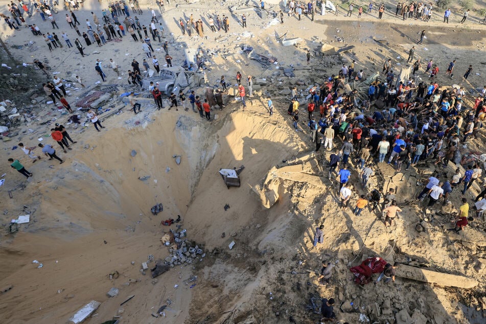 Eine Menschenmenge kommt zusammen, um einen israelischen Bombenkrater in Khan Yunis zu besichtigen.