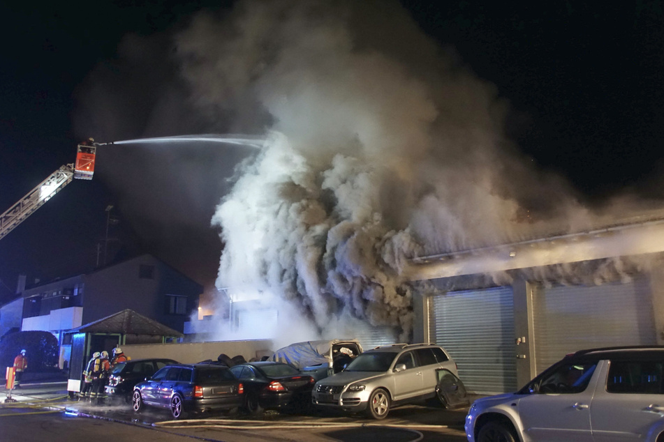 Feuerwehrleute löschen den Brand in der Autowerkstatt.