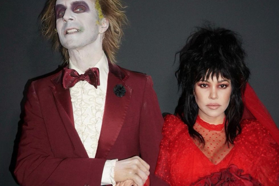 Kourtney Kardashian (r) and Travis Barker took spooky season to new heights with their Beetlejuice-themed costumes.